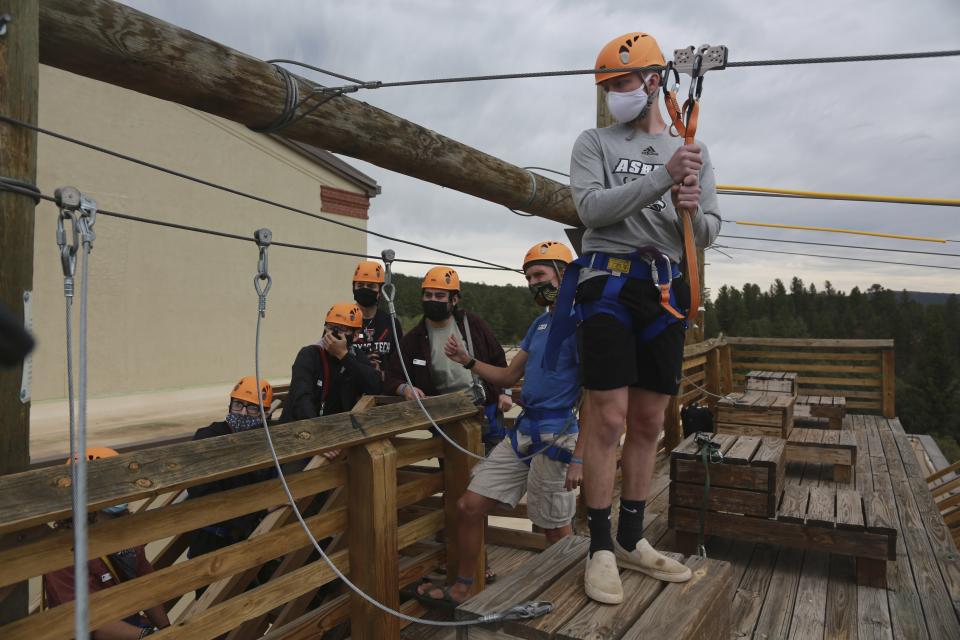 Glorieta Adventure Camp counselor Kole Linville, of Kentucky, trains on a zip line on Friday, May 21, 2021, in Glorieta, N.M., before campers arrive. The 3,000-bed camp outside Santa Fe opened up at a third of its normal capacity under pandemic restrictions after being closed last year. Campers and staff will be kept in pods of 10 or less, wear masks outside their sleeping quarters, and eat outdoors to prevent outbreaks. (AP Photo/Cedar Attanasio)