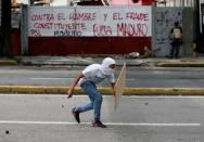 A demonstrator walks during clashes with riot security forces at a rally against Venezuela's President Nicolas Maduro's government in Caracas, Venezuela, July 28, 2017. The graffiti on the wall reads: "Against the hunger and the constituent fraud" and "Maduro leave". REUTERS/Andres Martinez Casares