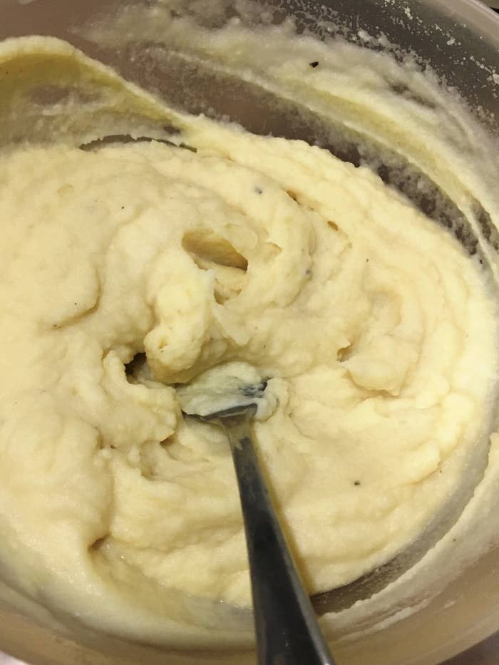A bowl of creamy mashed potatoes with a spoon resting in the mixture