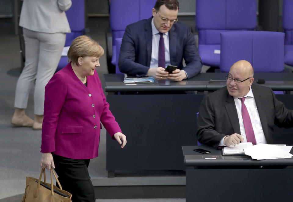 German Chancellor Angela Merkel, left, looks at German Economy Minister Peter Altmaier, right, as she arrives for a meeting of the German federal parliament, Bundestag, at the Reichstag building in Berlin, Germany, Thursday, April 23, 2020. In the center is German Health Minister Jens Spahn. (AP Photo/Michael Sohn)