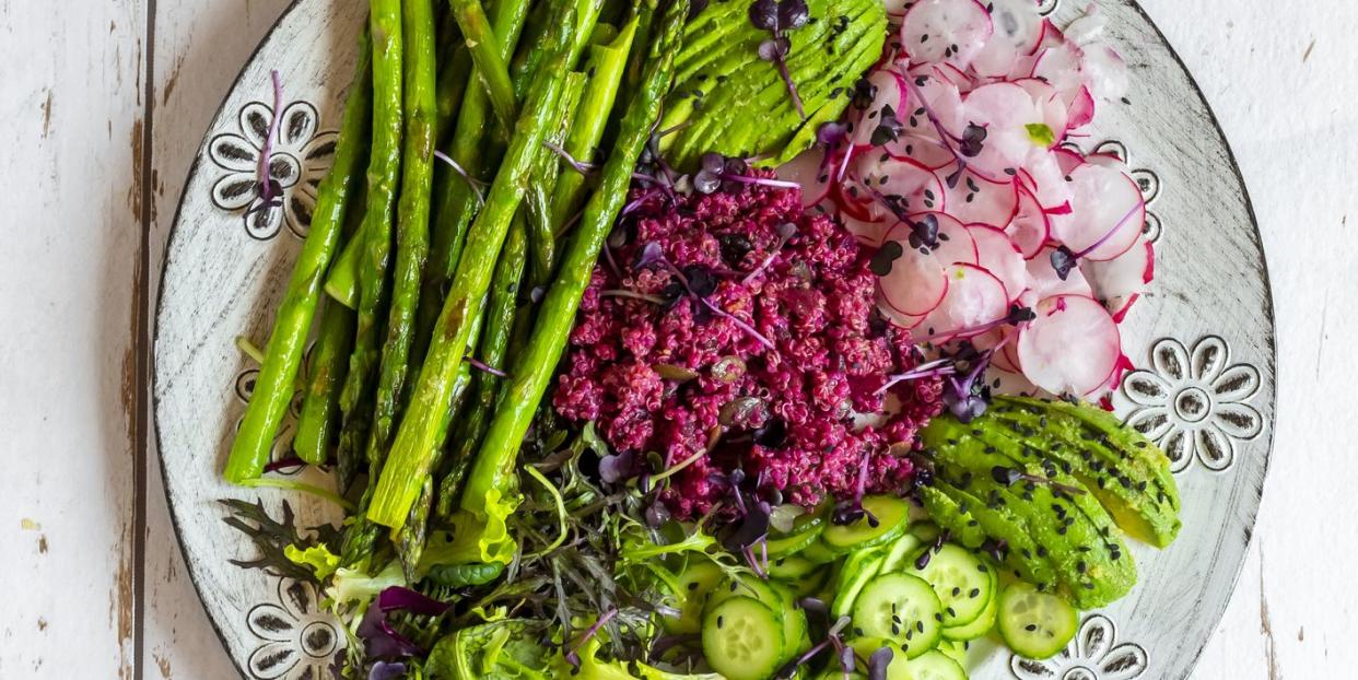 plate of springtime salad with green asparagus, red quinoa, avocado, red radishes, cucumber and sprouts