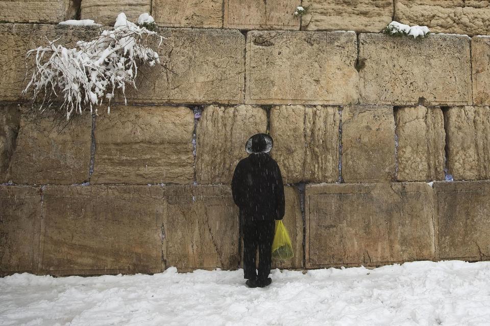 A man prays in the snow at the Western Wall, Judaism's holiest prayer site, in Jerusalem's Old City