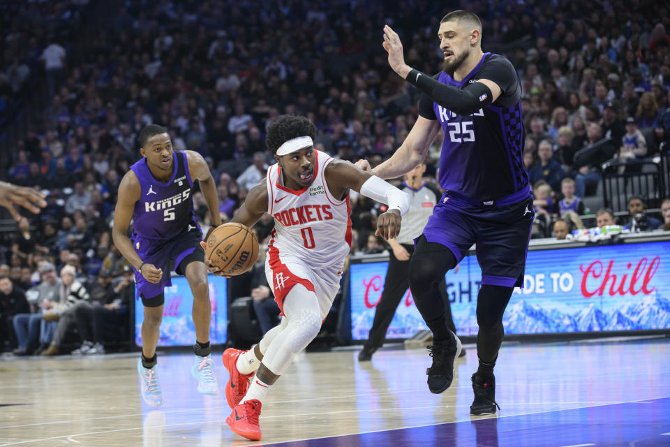 Houston Rockets guard Aaron Holiday (0) drives to the basket past Sacramento Kings guard De'Aaron Fox (5) and center Alex Len (25) during the first half of an NBA basketball game in Sacramento, Calif., Sunday, March 10, 2024. (AP Photo/Randall Benton)