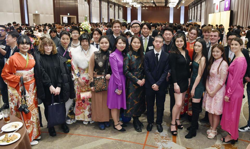 In this Jan. 13, 2020, photo, young foreigners, wearing ethnic clothes and kimonos, pose together for photographers as they attend a Coming-of-Age ceremony at Shinjuku district in Tokyo. In the district, one of Japan's most ethnically diverse town, more than 12 percent of its 348,000 residents are non-Japanese. On Monday, about half of some 4,000 people who celebrated coming of age at 20 were foreign residents.(Muneyuki Tomari/Kyodo News via AP)