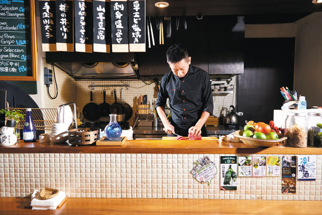 穿著西式廚師服裝的大廚於料理檯內切著生魚片，看到店內的日式料理以西式擺盤就可以了解這裡的創意。