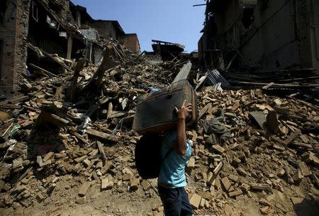 A man carrying a briefcase walks along the street near collapsed houses after last week's earthquake in Bhaktapur, Nepal May 2, 2015. REUTERS/Navesh Chitrakar