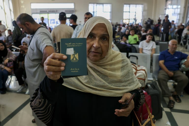 A woman shows her passport as Palestinian dual nationals and foreigners wait to cross the Rafah border crossing with Egypt, in the southern Gaza Strip, on November 7, 2023, (Mohammed ABED)