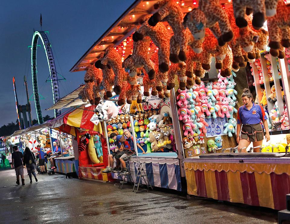 A game hawker waits for the crowds to come back after a summer rain at the Marshfield Fair on Friday, Aug. 26, 2022.