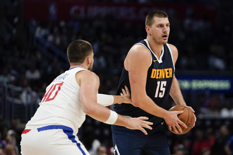 Denver Nuggets center Nikola Jokic, right, looks for to pass the ball as Los Angeles Clippers center Ivica Zubac guards, left, during the first half of an NBA basketball game, Thursday, Oct. 19, 2023, in Los Angeles. (AP Photo/Ryan Sun)