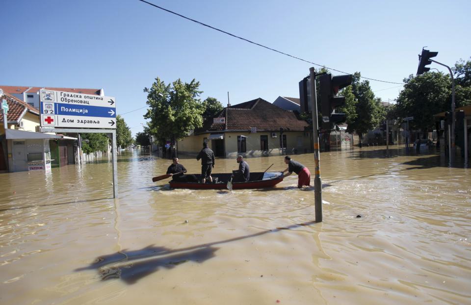 Local people travel on a boat in the flooded town of Obrenovac