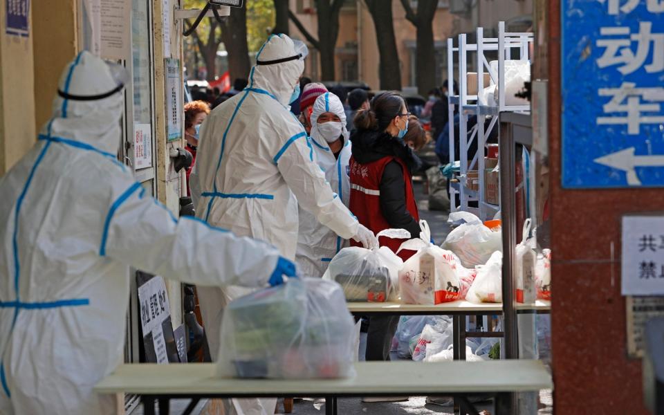 Volunteers wearing PPE arrange food supplies at the entrance of a residential block which is under restrictions, to halt the spread of Covid-19, on November 26 2021 in Shanghai, China.  - China News Service/China News Service