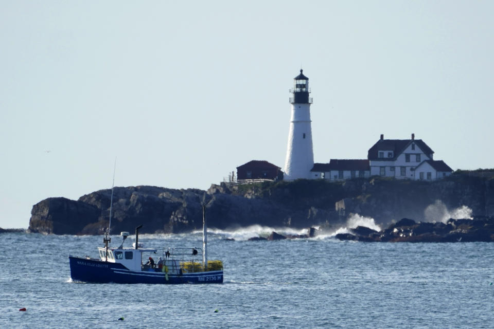 HOLD FOR RELEASE FRIDAY, SEPT. 25 - A lobster boat hauls traps near Portland Head Light, Monday, Sept. 21, 2020, off Cape Elizabeth, Maine. Prices for consumers and wholesalers were low in the early part of the summer, but picked up in August to the point where they were about on par with a typical summer. (AP Photo/Robert F. Bukaty)