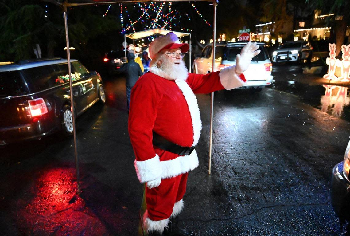 Santa waves as cars pass along Christmas Tree Lane, which is celebrating its 100th year, Thursday, Dec. 1, 2022 in Fresno.
