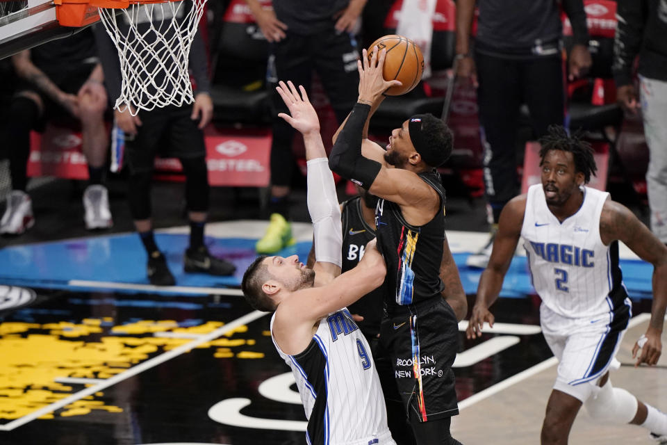 Orlando Magic center Nikola Vucevic (9) defends against Brooklyn Nets guard Bruce Brown (1) as Magic forward Al-Farouq Aminu (2) looks on during the third quarter of an NBA basketball game, Thursday, Feb. 25, 2021, in New York. (AP Photo/Kathy Willens)