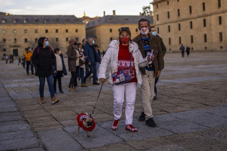 Personas con mascarillas para frenar los contagios de COVID-19 caminan por San Lorenzo de El Escorial, España, el domingo 2 de enero de 2022. (AP Foto/Manu Fernández)