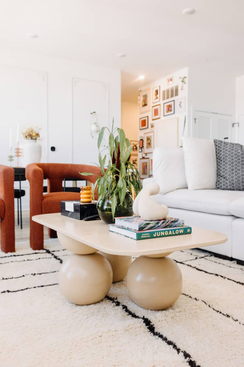 white living room with white sofa, black, neutral and white decor, and lots of curved edge furniture