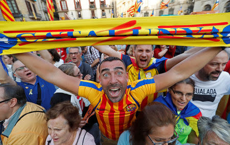 A man displays a scarf featuring an Estelada (Catalan separatist flag) design, as he reacts at Sant Jaume Square after the Catalan regional parliament declares independence from Spain in Barcelona, Spain October 27, 2017. REUTERS/Yves Herman