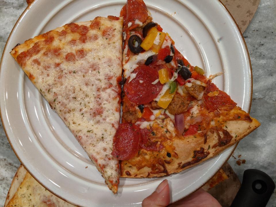 Two slices of pizza - one cheese and another loaded with veggies - on a white plate