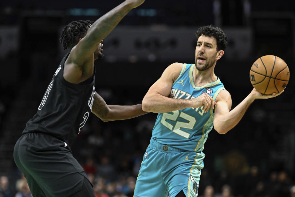 Charlotte Hornets guard Vasilije Micic (22) looks to pass the ball away from Brooklyn Nets forward Dorian Finney-Smith during the first half of an NBA basketball game, Saturday, March 9, 2024, in Charlotte, N.C. (AP Photo/Matt Kelley)
