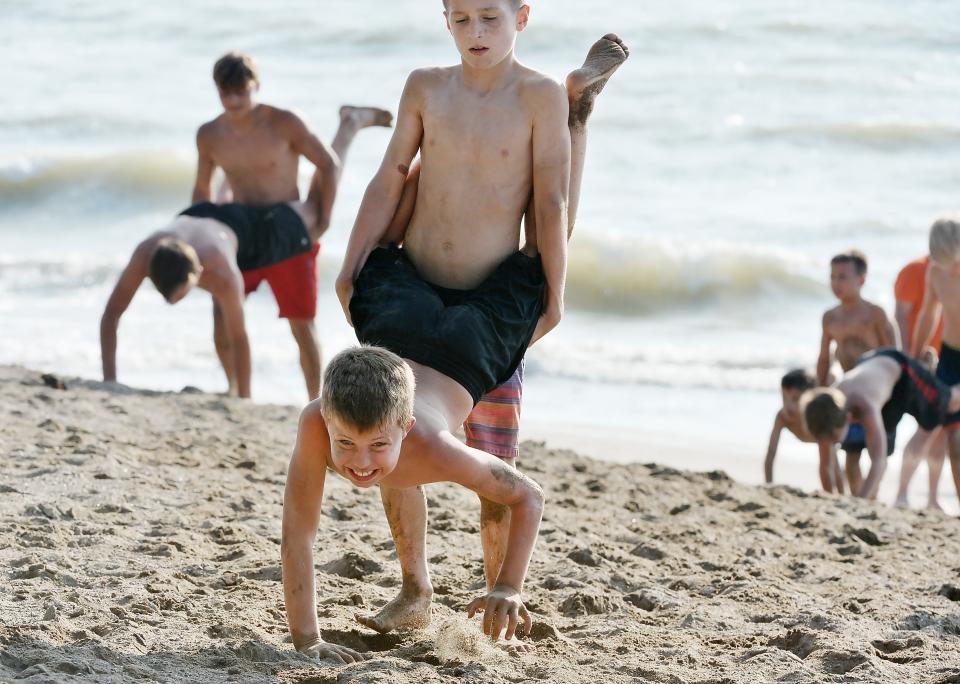 Rambler Wrestling Club members T.J. Markijohn, 9, top, and Austin Buck, 10, take turns climbing a slope on Beach 7 during a workout at Presque Isle State Park.