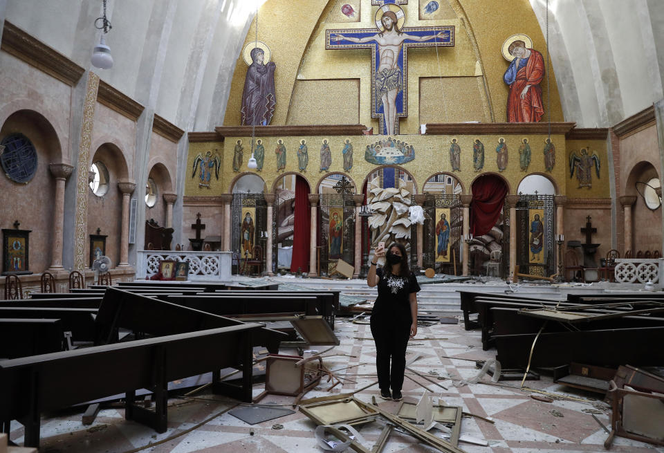 A woman takes pictures by her mobile phone for a damaged church, after an explosion hit the seaport of Beirut, Lebanon, Wednesday, Aug. 5, 2020. Residents of Beirut awoke to a scene of utter devastation on Wednesday, a day after a massive explosion at the port sent shock waves across the Lebanese capital. (AP Photo/Hussein Malla)