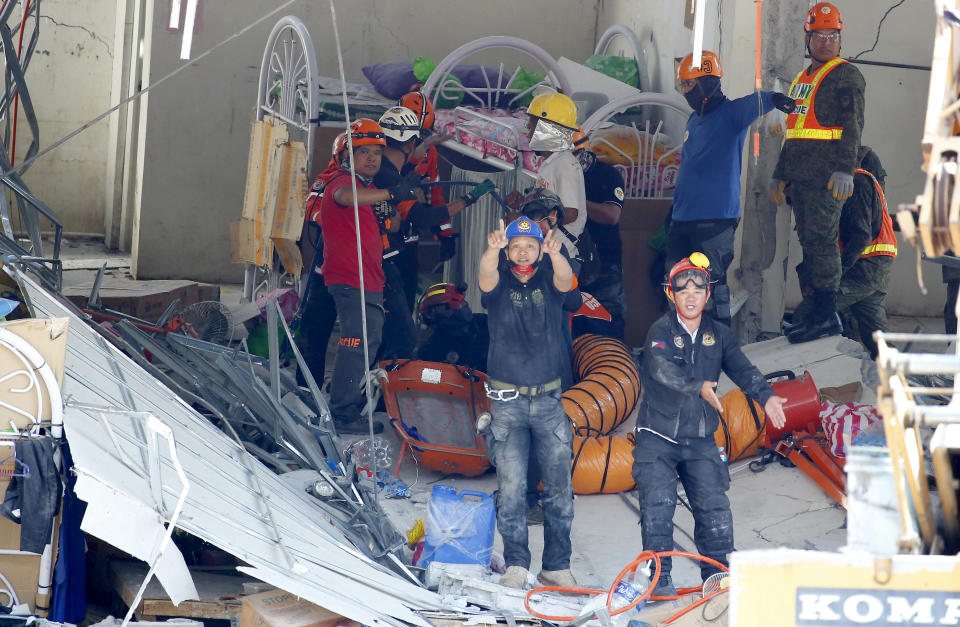 Rescuers gesture to clear the way following the discovery of another survivor in Monday's magnitude 6.1 earthquake that caused the collapse of a commercial building in Porac township, Pampanga province north of Manila, Philippines Tuesday, April 23, 2019. A strong earthquake struck the northern Philippines Monday trapping some people in a collapsed building, damaged an airport terminal and knocked out power in at least one province, officials said. (AP Photo/Bullit Marquez)