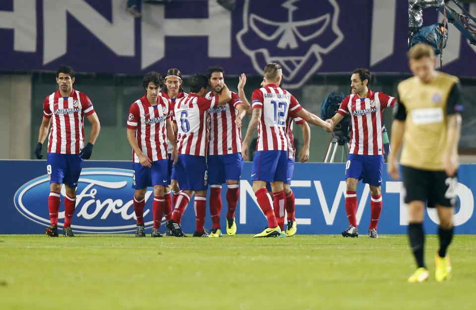 Atletico Madrid players celebrate scoring a goal, as Austria Vienna's Daniel Royer (R) walks away, during their Champions League Group G soccer match in Vienna October 22, 2013. REUTERS/Dominic Ebenbichler (AUSTRIA - Tags: SPORT SOCCER)