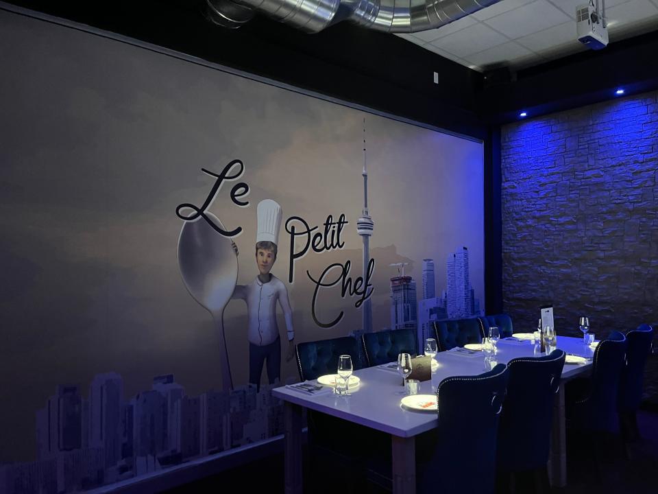 The inside of Le Petit Chef, with a large sign and set table