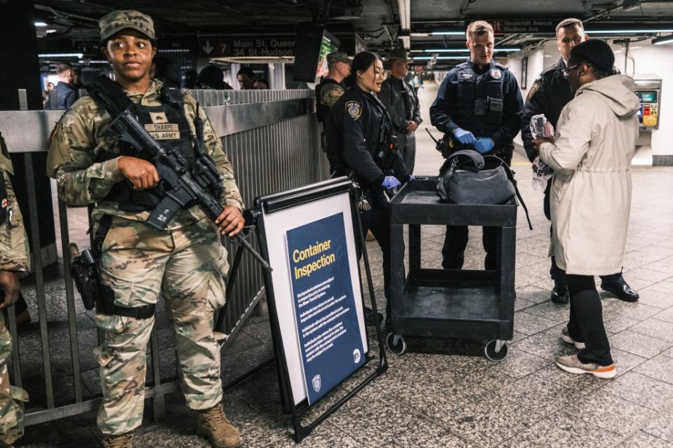A National Guard member stands watch as MTA police conduct a random bag check at the entrance to the 7 train at Grand Central Station on Wednesday. Stephen Yang