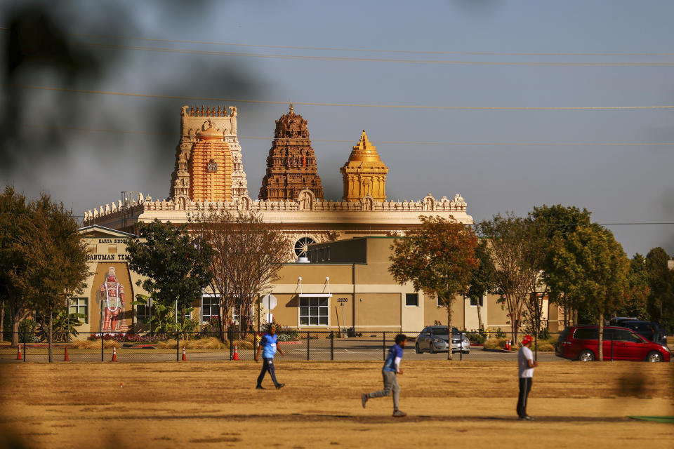With the Karya Siddhi Hanuman Temple in the background, a cricket match between the Dallas Cricket Connections and the Kingswood Cricket Club is played on a field adjacent to Roach Middle School in Frisco, Texas, Saturday, Oct. 22, 2022. The teams play in the City of Frisco Cricket league. (AP Photo/Andy Jacobsohn)