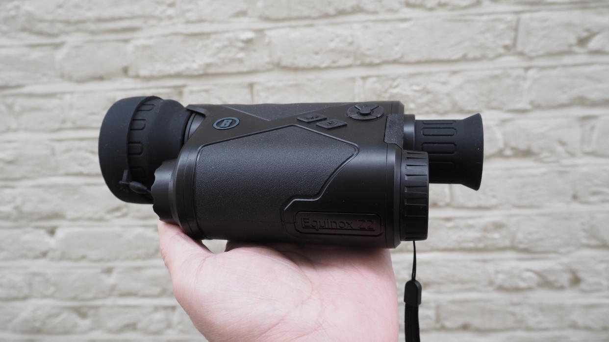  Bushnell Equinox Z2 6x50 Night Vision Monocular held in a hand against a white wall. 