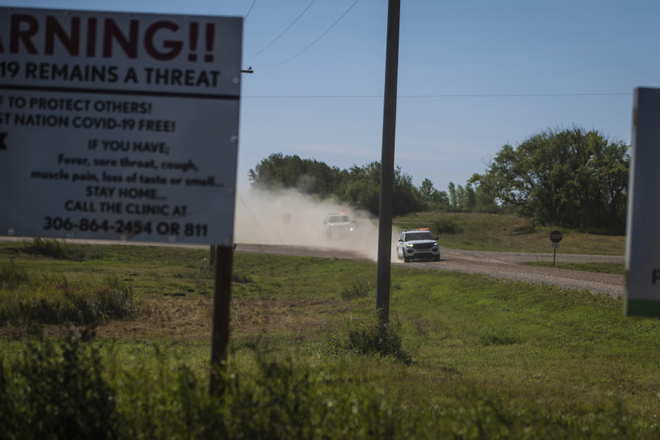 Canadian law enforcement personnel rush to surround a home on the James Smith Cree First Nation reservation in Saskatchewan, Canada, Tuesday, Sept. 6, 2022, as they search for a suspect in a series of stabbings. (AP Photo/Robert Bumsted)