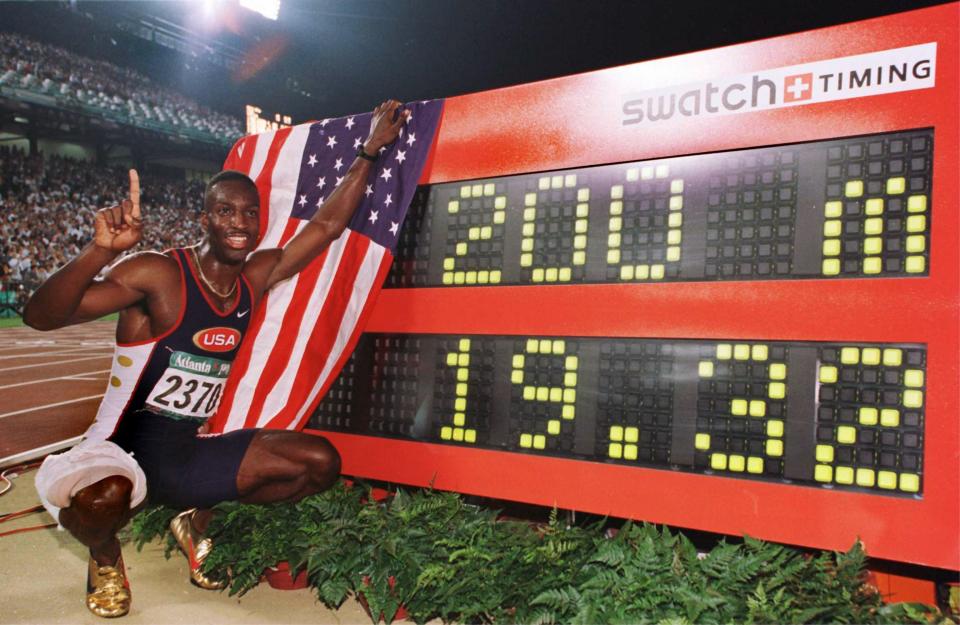 Michael Johnson poseert naast zijn toenmalige WR-tijd op de 200 meter op de Olympische Spelen van 1996.  (Mike Powell/Getty Images)