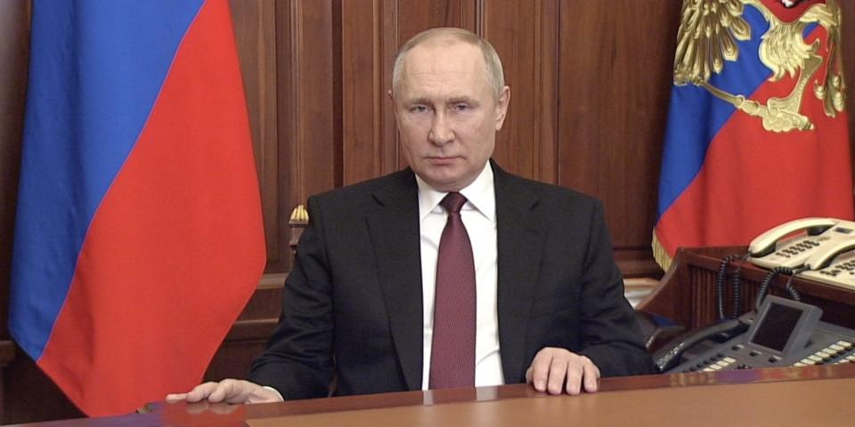 Russian President Vladimir Putin seated behind a desk.