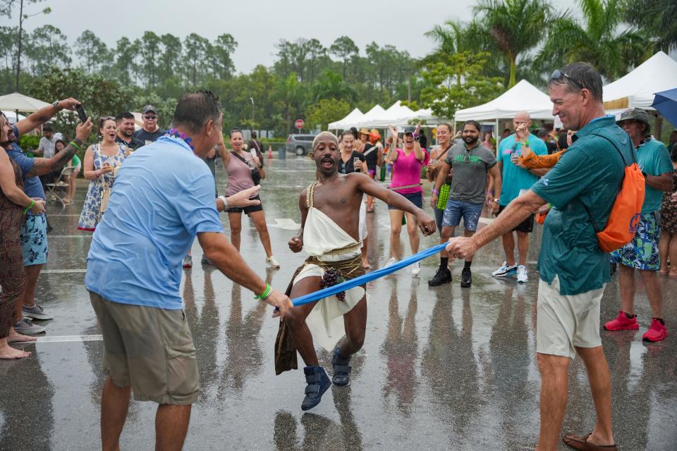 Patrons use a t-shirt for a makeshift game of limbo during the USA Today Wine and Food Experience at Paradise Coast Sports Complex in Naples on Saturday, Sept. 30, 2023.