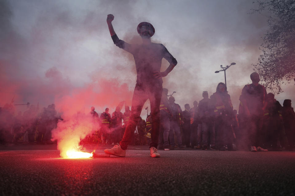 A protester uses a flare during a demonstration in Lyon, central France, Tuesday, Dec. 17, 2019. Workers at the Eiffel Tower, teachers, doctors, lawyers and people from across the French workforce walked off the job Tuesday to resist a higher retirement age, or to preserve a welfare system they fear their business-friendly president wants to dismantle. (AP Photo/Laurent Cipriani)