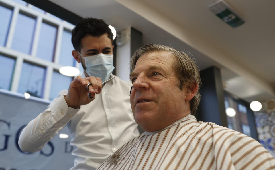 The Lord Mayor of London William Russell gets his hair cut by Ali Baltar, owner of the Grooming Lounge in the City of London, Monday, April 12, 2021. Millions of people in England will get their first chance in months for haircuts, casual shopping and restaurant meals on Monday, as the government takes the next step on its lockdown-lifting road map. (AP Photo/Alastair Grant)