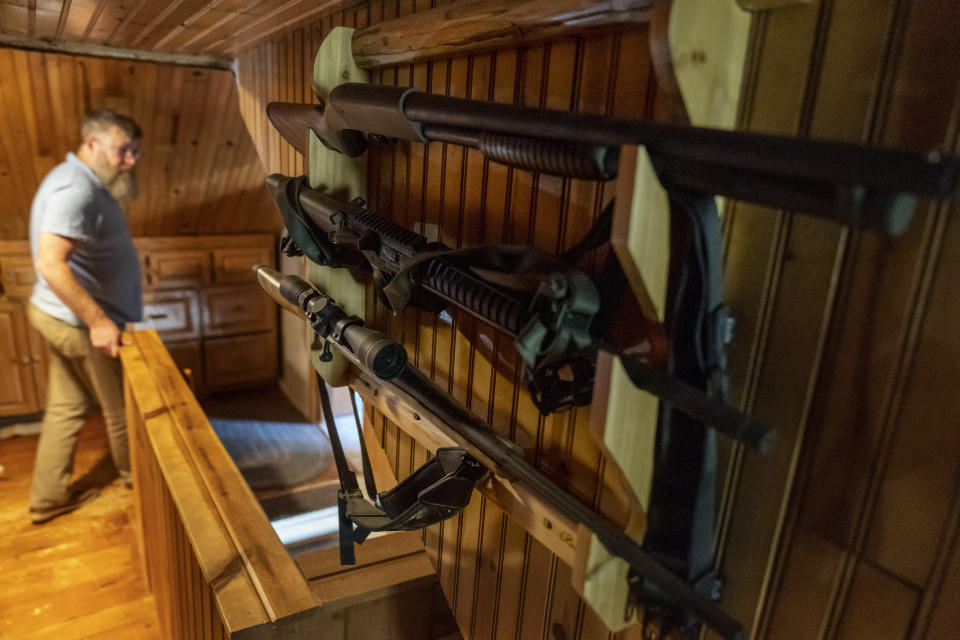 Mark Carlson walks past a gun rack holding his firearms at his home in Hammond, Wis., Wednesday, Sept. 28, 2022. "I'm not a big gun guy," says Carlson, whose weapons include pistols, a shotgun, an AR-15 rifle, 10 loaded magazines and about 1,000 additional rounds. "For a lot of people that's just a start." (AP Photo/David Goldman)