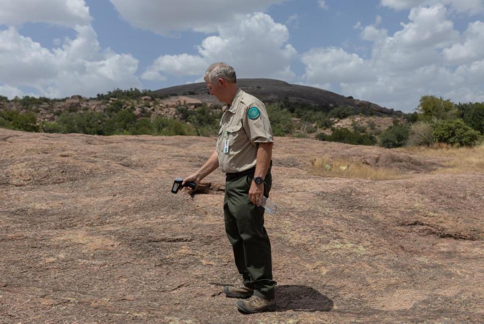 Superintendent Doug Cochran checks the surface temperature of the granite floor at Enchanted Rock State Natural Area, located north of Fredericksburg, on a hot summer day, July 26, 2023. The surface temperature in the area was around 140 degrees Fahrenheit.
