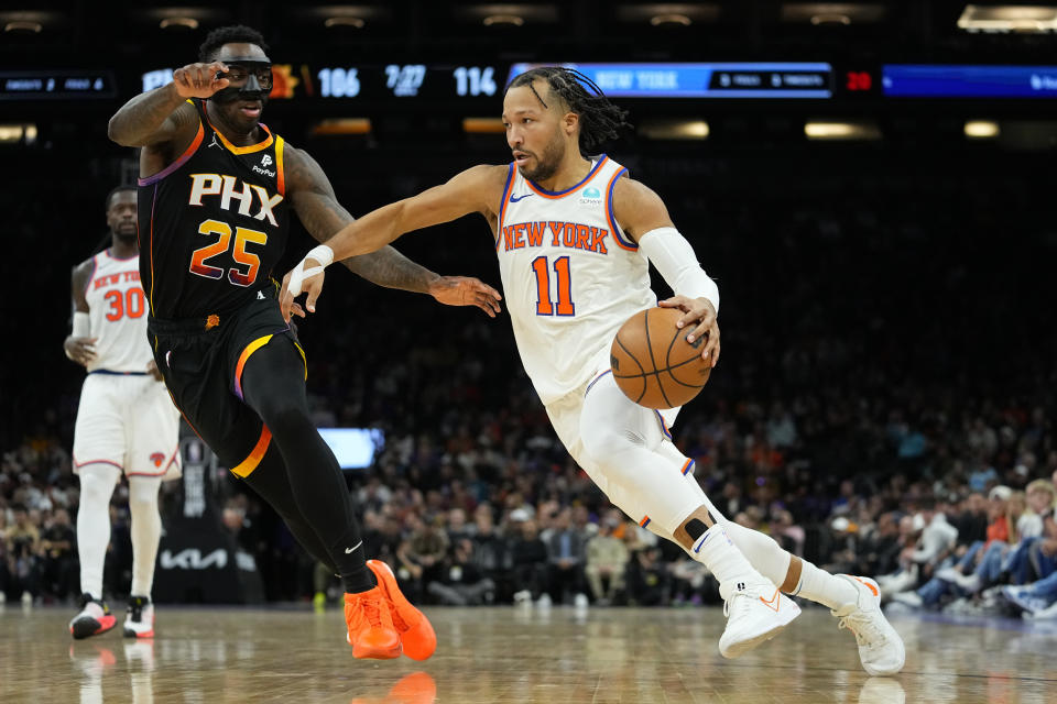 New York Knicks guard Jalen Brunson (11) drives as Phoenix Suns forward Nassir Little (25) defends during the second half of an NBA basketball game, Friday, Dec. 15, 2023, in Phoenix. (AP Photo/Matt York)