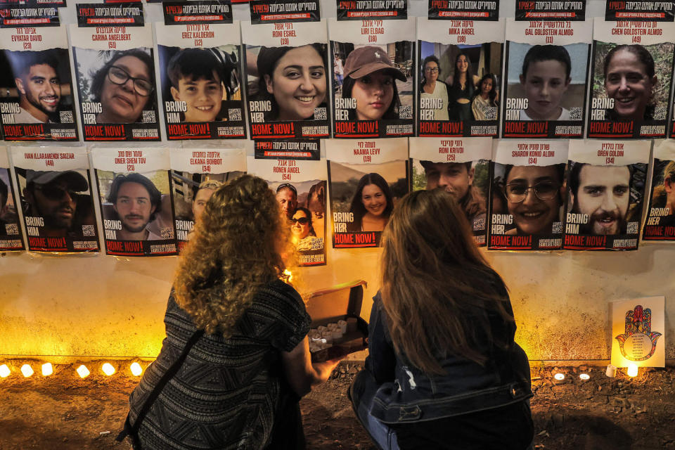People light candles beneath a wall showing posters identifying hostages abducted by Palestinian militants during the October 7 attack, in Jerualem (Ahmad Gharabli / AFP via Getty Images file )