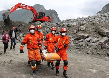 Rescue workers carry a victim at the site of a landslide that occurred in Xinmo Village, Mao County, Sichuan province, China, June 25, 2017. China Daily via REUTERS
