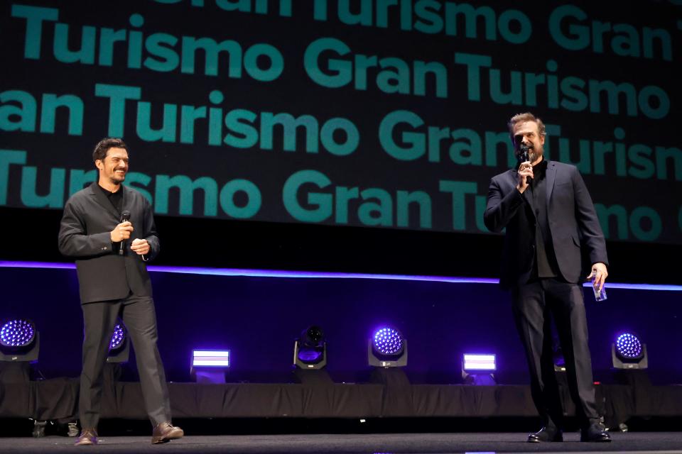 Orlando Bloom and David Harbour with a Gran Turismo sign behind them