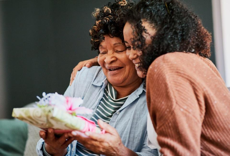 shot of a young woman giving her elderly relative a present on the sofa at home