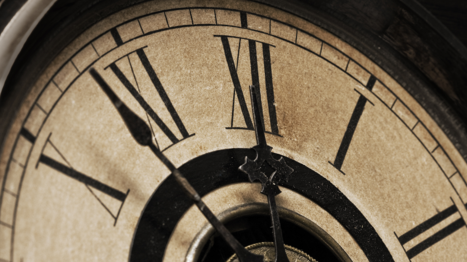 A close-up of the face of an antique grandfather clock that is going to strike midnight shortly in "High Noon on the Waterfront" directed by Billy Shebar and David Roberts.