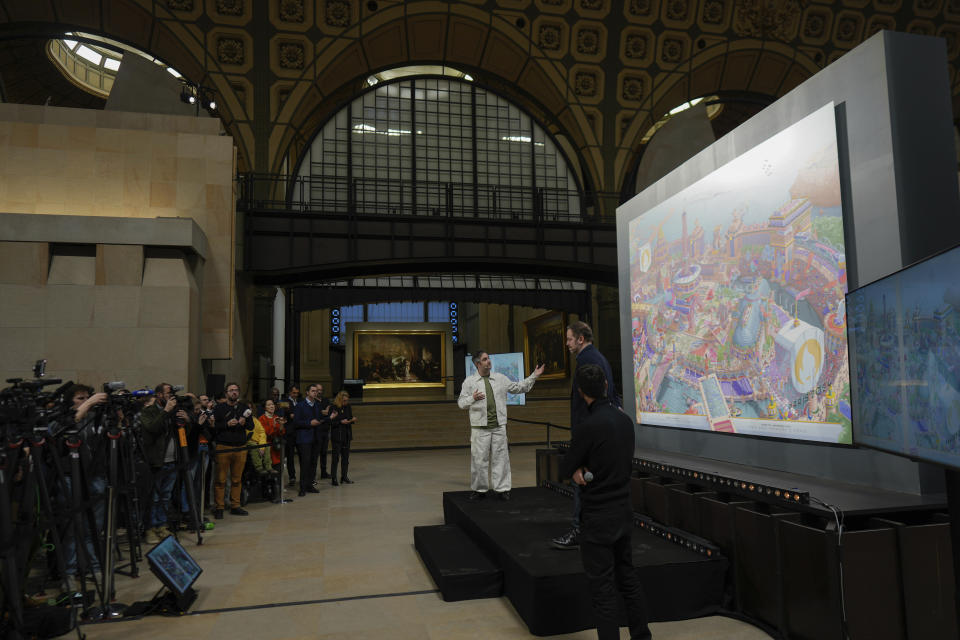 CORRECTS SPELLING OF FIRST NAME FROM HUGO TO UGO - French artist Ugo Gattoni, center, gestures during the presentation of the Paris 2024 Olympic and Paralympic posters at the Musee d'Orsay, in Paris, Monday, March 4, 2024. Vibrant colors and striking landmarks illuminate posters for the Paris Olympic Games in an Art Deco style inspired by the city's flamboyant past. (AP Photo/Thibault Camus)