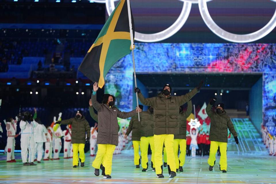 Benjamin Alexander and Jazmine Fenlator-Victorian, of Jamaica, carry their national flag into the stadium during the opening ceremony of the 2022 Winter Olympics, Friday, Feb. 4, 2022, in Beijing. (AP Photo/Jae C. Hong)