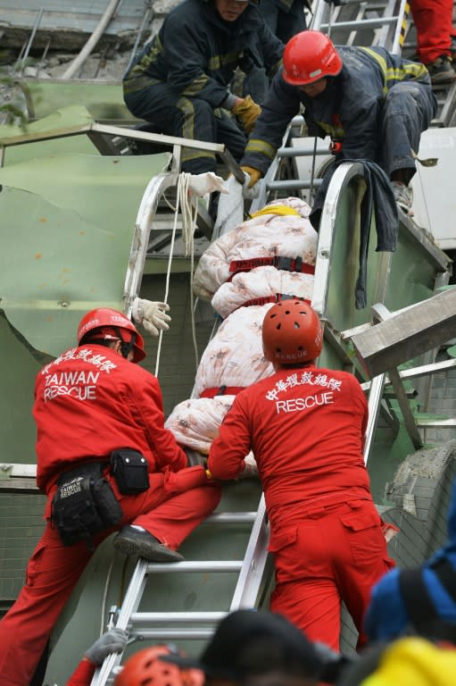 Rescue personnel carry the body of a victim at the site of a collapsed building in the southern Taiwanese city of Tainan following a strong 6.4-magnitude earthquake that struck the island early on February 6, 2016