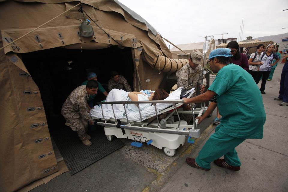 A woman and her newborn baby are transferred, after delivery in a Chilean Army field hospital, in Iquique, Chile, Friday, April 4, 2014. Coastal residents of Chile's far north have spent sleepless nights outside their homes as aftershocks continued following a magnitude-8.2 earthquake early in the week that damaged several thousand homes and caused six deaths. (AP Photo/Luis Hidalgo).