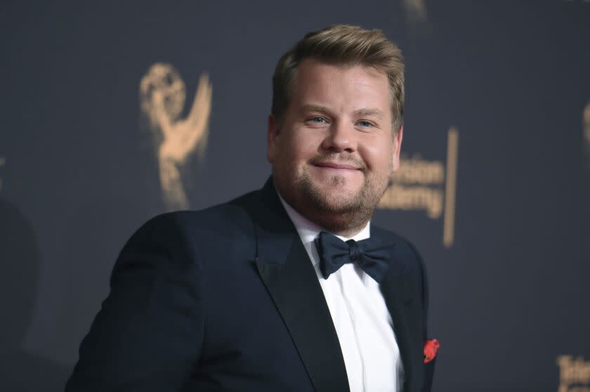 A man in a tuxedo smiles as he arrives at an award show